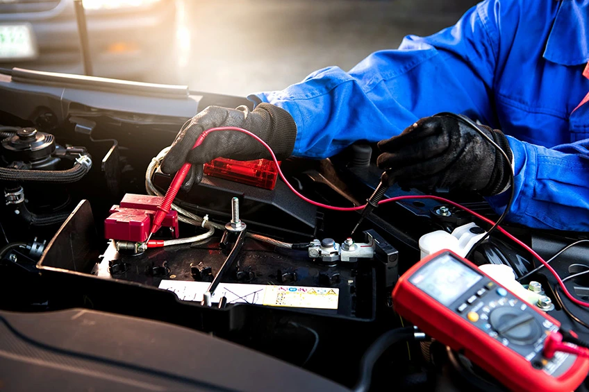 a mechanic demonstrating how to test a car battery